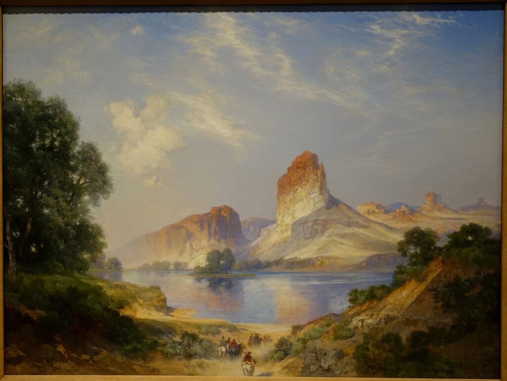 The cliffs above the Green River glowing at low light, with riders on the far bank.