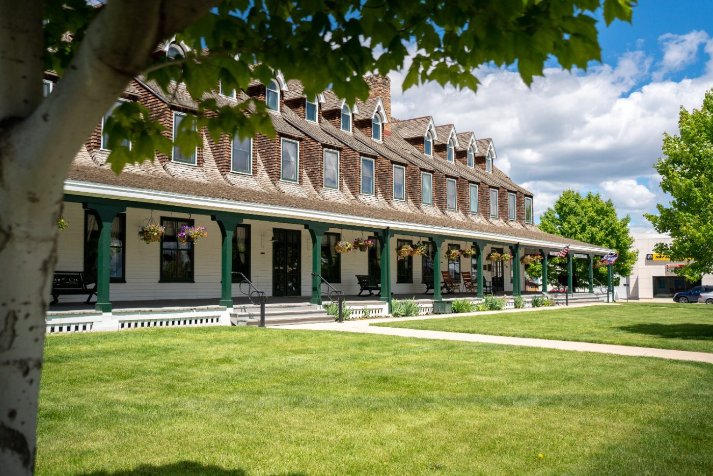 The Historic Sheridan Inn, a long two-story building with dormers, behind a green lawn