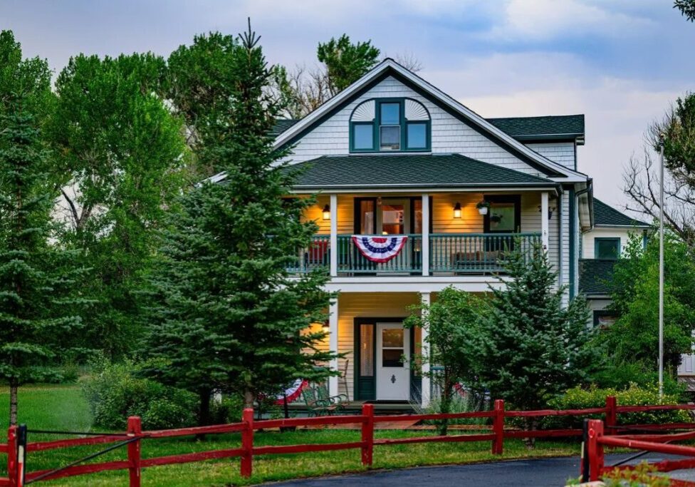 The Historic Elk Mountain Hotel, a white two-story building with a red fence, among trees