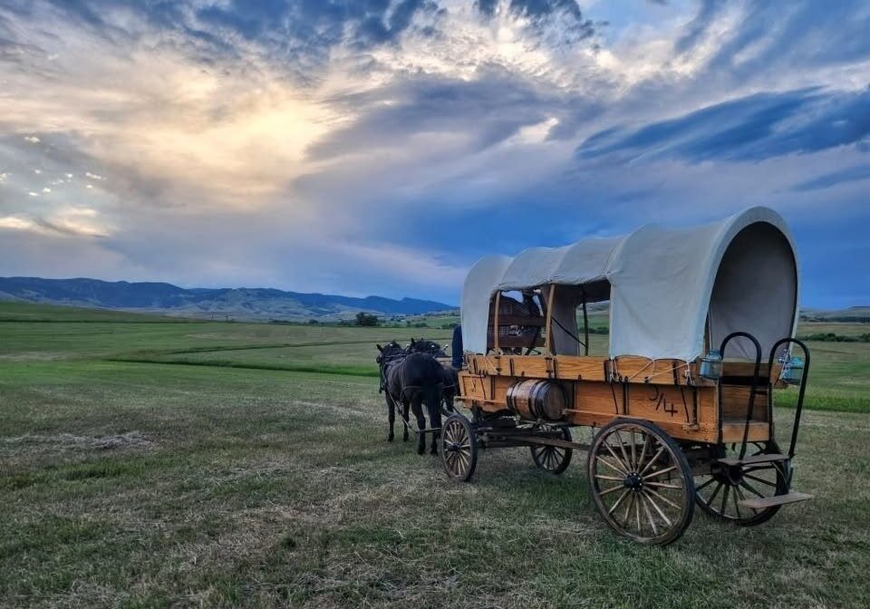 Covered wagon and team on the prairie at Fort Phil Kearny State Historic Site at sunset